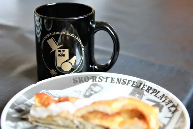 Krus og morgenmad med skorstensfejerlogo